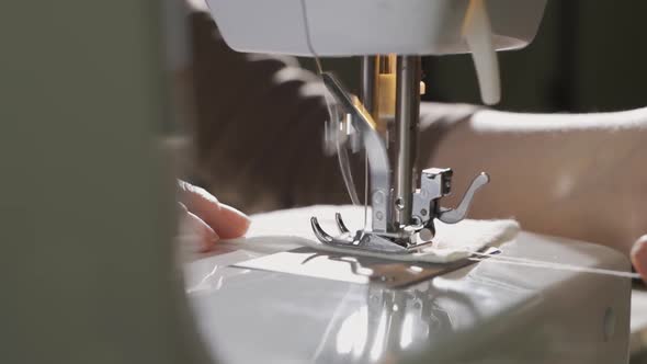 A Female Hand Pushes Material Through a Sewing Machine