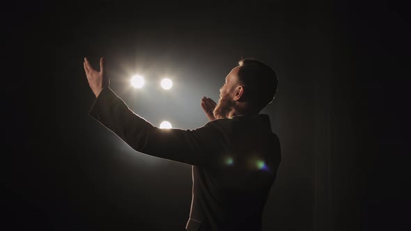 A Man is Standing on the Stage and Clapping His Hands