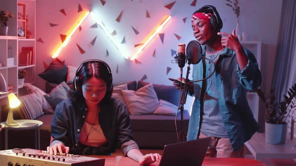 Asian Woman and Black Rapper Recording Music in Home Studio