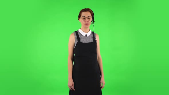 Funny Girl in Round Glasses Is Talking on Headphones, Call Center. Green Screen
