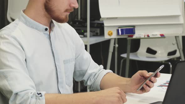 Handsome Young Bearded Businessman Using Smart Phone at Work