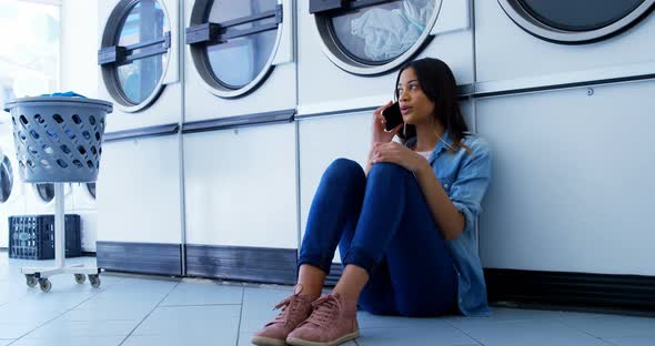 Woman talking on mobile phone at laundromat