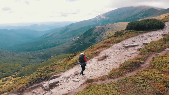 Aerial View of a Traveler Photographer with Backpack Climbing By Mountain Range