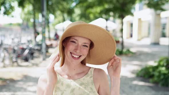 Young Happy Woman Wearing Hat Standing on Summer City Street Portrait