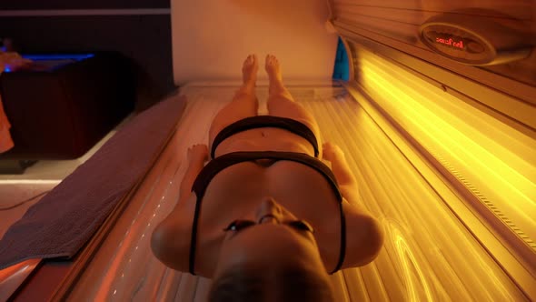 Sun Treatments in a Horizontal Solarium Young Female Takes a Sun Bath in a Solarium Warm Light