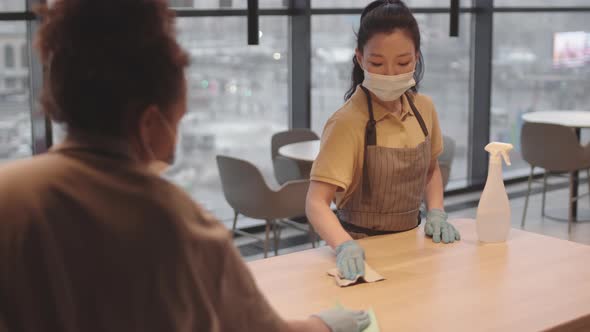 Colleagues Disinfecting Table in Restaurant