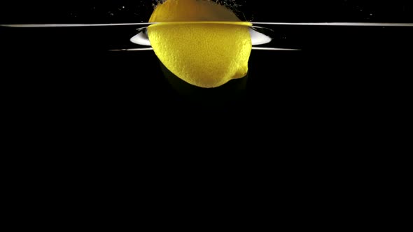 Slo-motion whole lemon falling on water