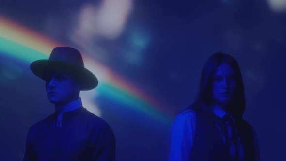 Couple in Creative Costumes in Dark Studio with Rainbow Light