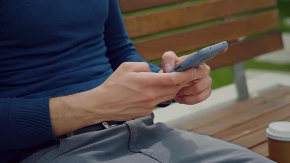 Man using mobile phone. Writing a message on smartphone outdoor park.