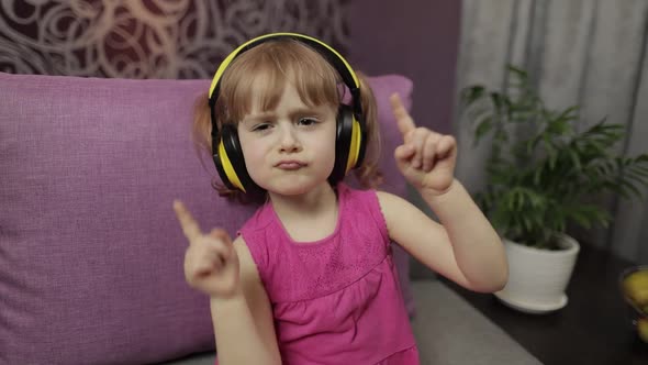 Little Child Girl in Headphones Enjoying Listen Music. Dancing on Sofa at Home