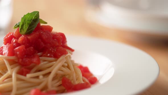 Camera follows pouring olive oil over fresh tomato sauce spaghetti in plate. Slow Motion.