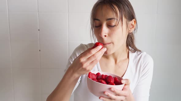 Woman Holds Bowl with Strawberry and Eats Berries