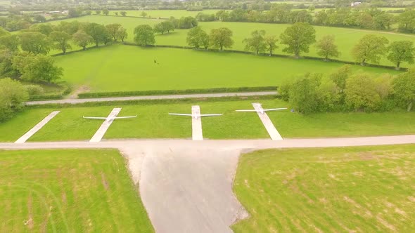 rising view of several parked hand gliders beside runway