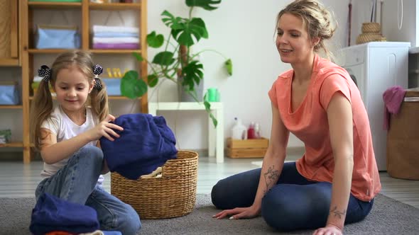 Mom and Child High Five Each Other After Finishing Folding Laundry Domestic Chore