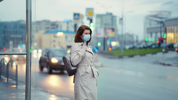 Woman in Mask Waiting for Bus in the Evening