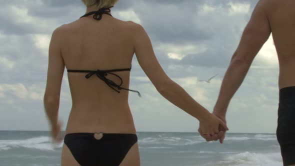 Couple holding hands walking along a beach
