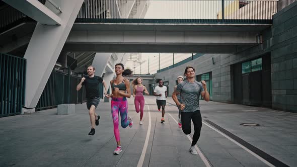 Young Athletes in Excellent Physical Shape are Running Around the Stadium