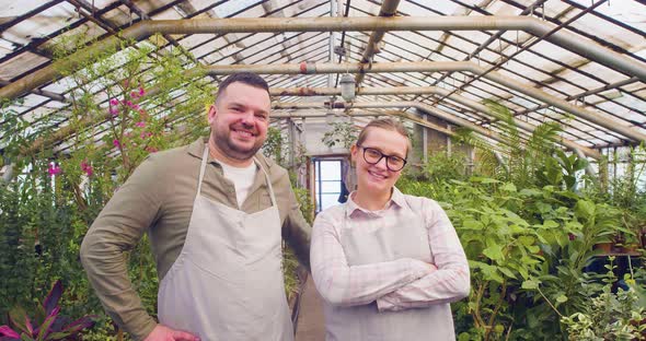 Young Couple of Farmers Stand in Front of the Camera in the Greenhouse of a Hydroponic Farm