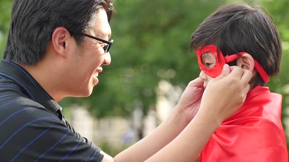 cAsian Father And His Son Playing Together In The Park,Boy In Superhero Costume