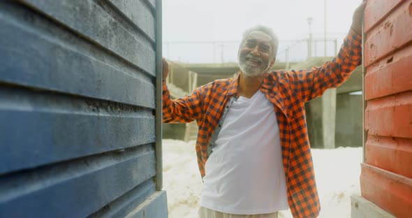 Front view of happy active senior African American man standing at beach hut on a sunny day 4k