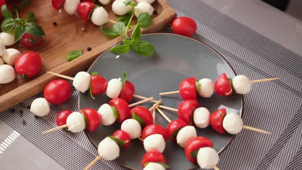 Putting Caprese Canapes with Cherry Tomatoes and Mozzarella Cheese Balls on a Plate