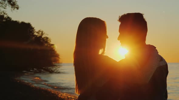 Romantic Multiethnic Couple Hugging at Sunset, Standing Against the Sea