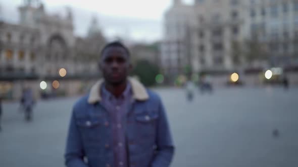 African American guy in stylish clothing walking on street