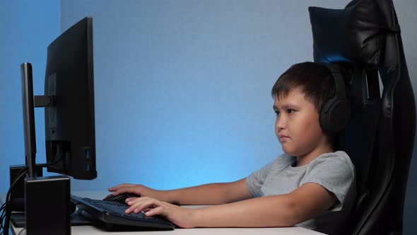 Boy with Headphones Playing on the Computer