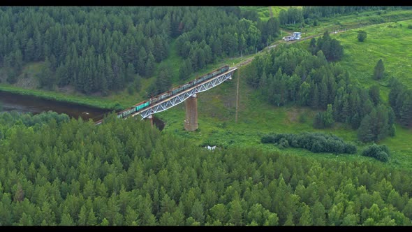 Aerial View of a Train Crossing a Railway Bridge Over a River in Summer