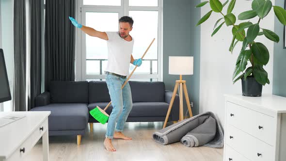 Man Cleaning the House and Having Fun Dancing with a Broom