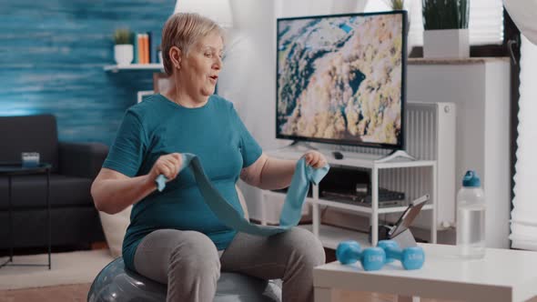 Aged Person Pulling Resistance Band on Fitness Toning Ball