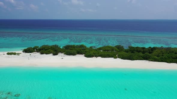 Bright azure lagoon and large coral reef around tiny tropical island with untouched white sandy beac