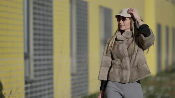 Rich Woman Dressed Luxury Fur Jacket and Cap Is Walking Outdoors at Sunny Day Fashionista in Big