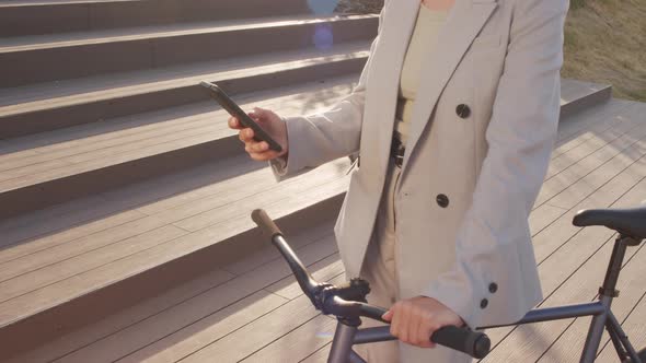 Woman with Bike Scrolling on Smartphone Outdoors