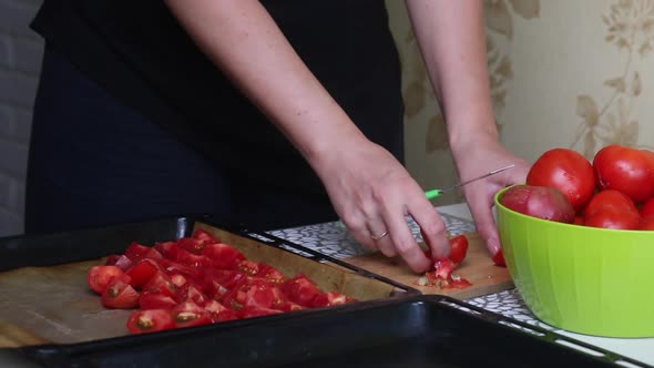 The Woman Cuts The Tomatoes On A Cutting Board And Puts Them On A Baking Sheet.