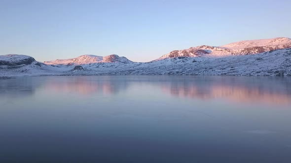 Sunlight and mountain reflected on the glassy surface of a fjord