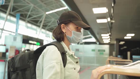 A Woman in a Mask and with a Backpack Behind Her Back Near the Checkin Desk to Board the Aircraft