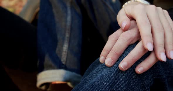 Close Female Hand Caresses Male Hand Leaned on Knee