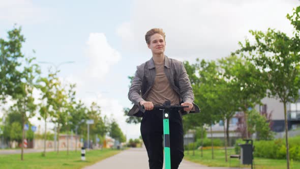 Young Man Riding Electric Scooter on City Street