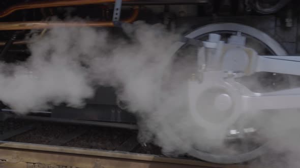 Close up shot of steam locomotive wheels and pistons driving slowly in reverse