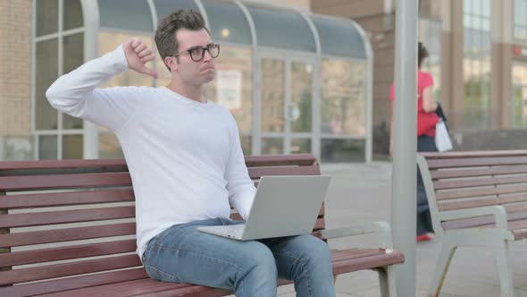 Thumbs Down By Young Man with Laptop Sitting on Bench