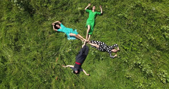 Aerial View Of Four Girls Falling Into The Grass. Rest And Joy