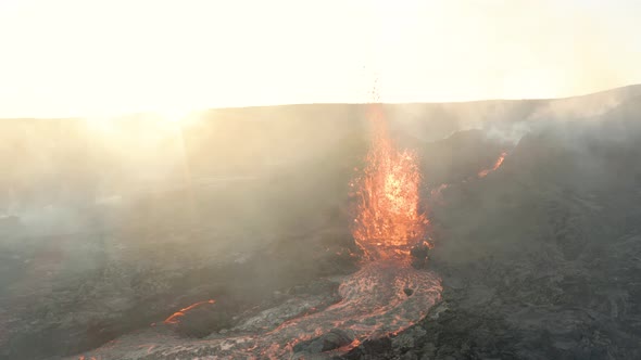 Lava Fountain From Volcanic Crater During Eruption With Bright Sun In Background.