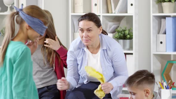 Friendly Counselor Encouraging Blindfolded Girl during Action Game