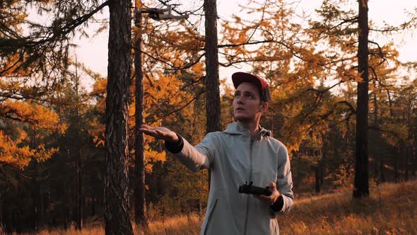 Drone Pilot Puts the Drone in His Hand on a Background of Sunset in Forest