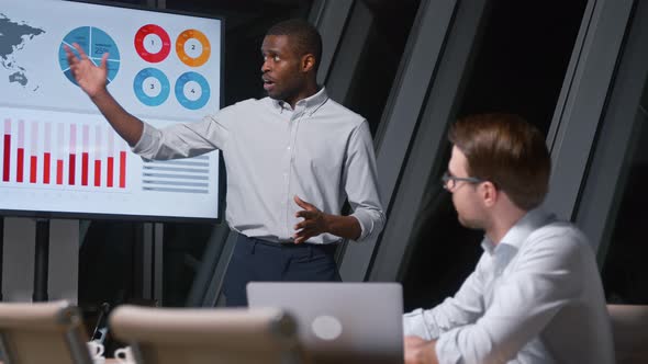 Young african american man giving presentation to corporate leader using tv multimedia