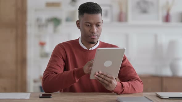 African Man using Tablet while Sitting in Office