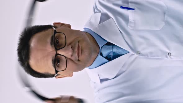 Vertical Shot Handsome Doc in Lab Coat Puts on Stethoscope Examining Patient White Background