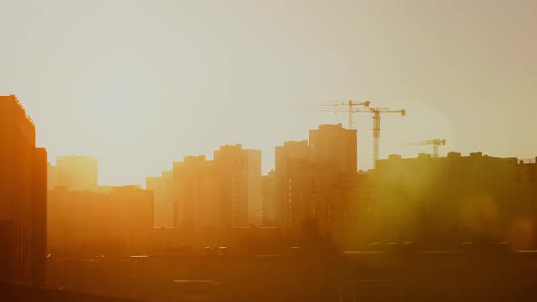 Construction Site in Warm Sunrise Light, Tower Cranes Working on Residential Building Morning Time