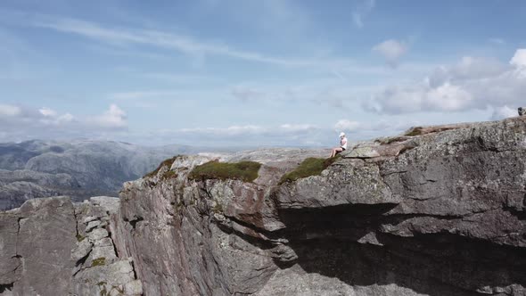 Aerial Shot of a Woman Sitting By the Edge of a Cliff at Pulpit Rock